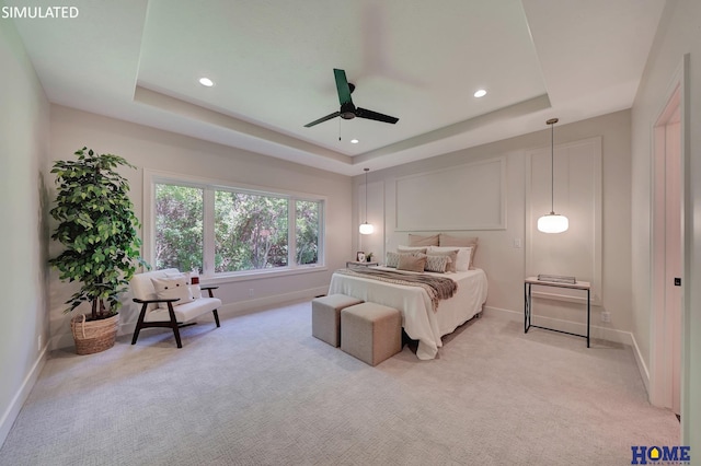 carpeted bedroom featuring ceiling fan and a tray ceiling