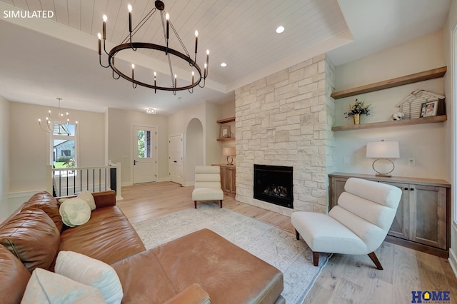 living room with light hardwood / wood-style floors, wooden ceiling, a notable chandelier, a fireplace, and built in shelves