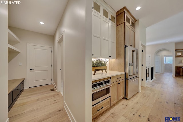 kitchen featuring light wood-type flooring, stainless steel appliances, light brown cabinets, and tasteful backsplash