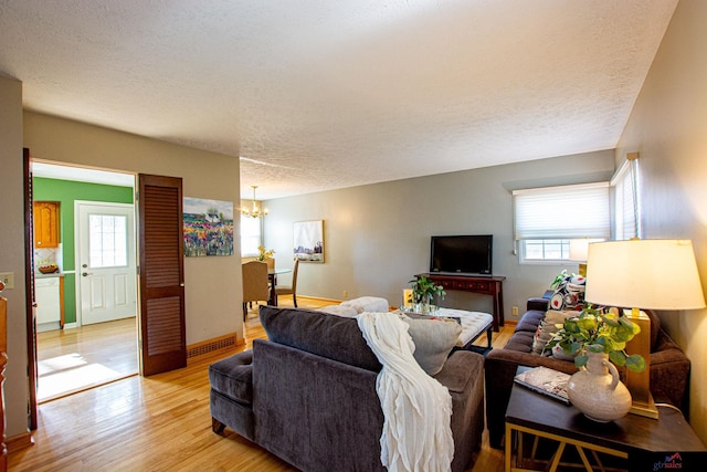 living room featuring a textured ceiling, an inviting chandelier, and light hardwood / wood-style flooring