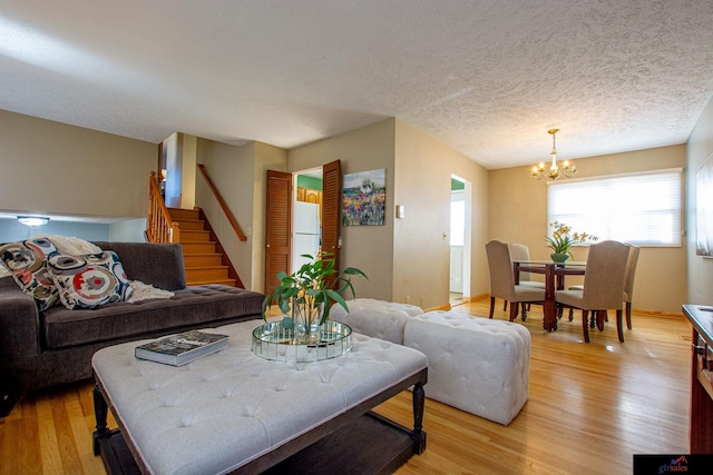 living room featuring a textured ceiling, an inviting chandelier, and light hardwood / wood-style flooring