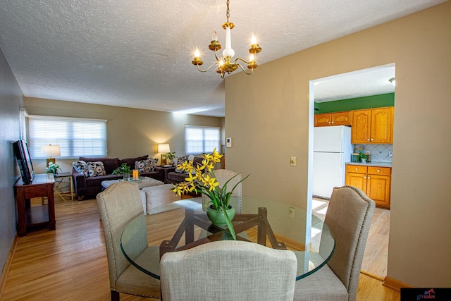 dining room with a textured ceiling, an inviting chandelier, and light hardwood / wood-style floors