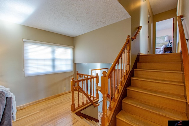 stairway featuring a textured ceiling and wood-type flooring