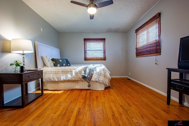 bedroom featuring ceiling fan, wood-type flooring, and a textured ceiling