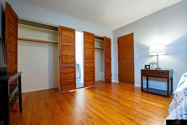 bedroom featuring hardwood / wood-style flooring, a textured ceiling, and two closets