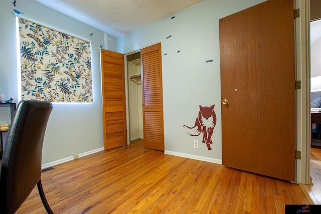 unfurnished office with light wood-type flooring and a textured ceiling