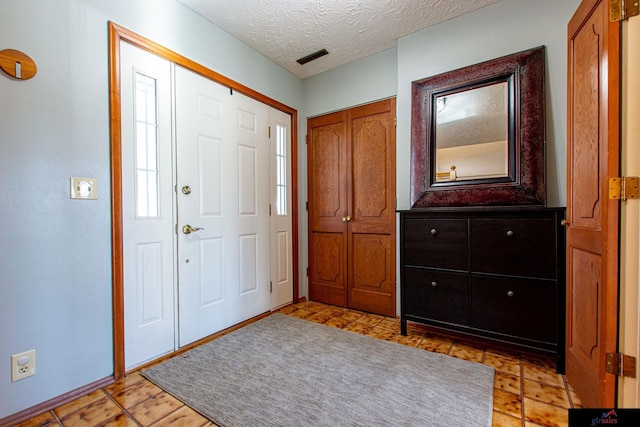 foyer with light tile patterned floors and a textured ceiling