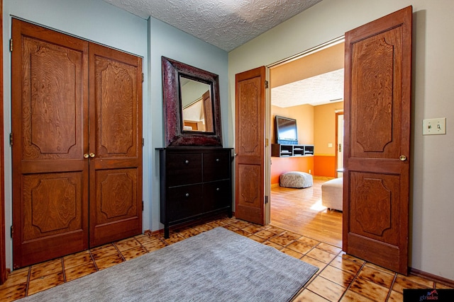 hallway with a textured ceiling and light tile patterned flooring