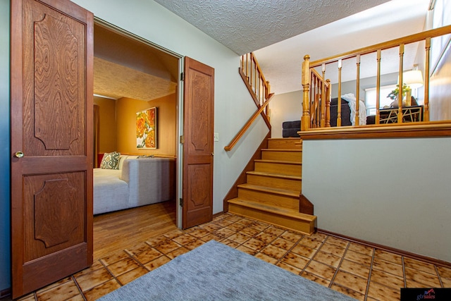 stairs with tile patterned flooring and a textured ceiling