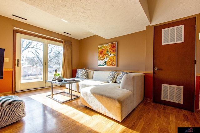 living room featuring wood-type flooring and a textured ceiling