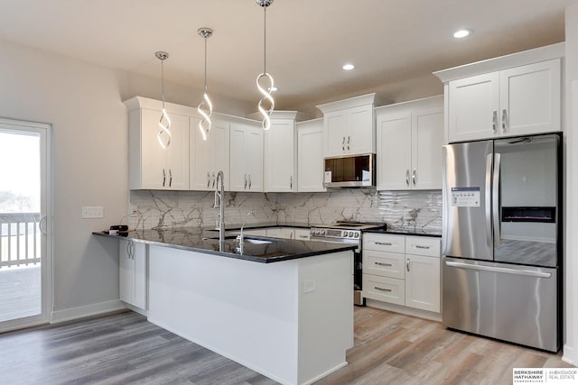 kitchen featuring kitchen peninsula, sink, white cabinetry, hanging light fixtures, and stainless steel appliances