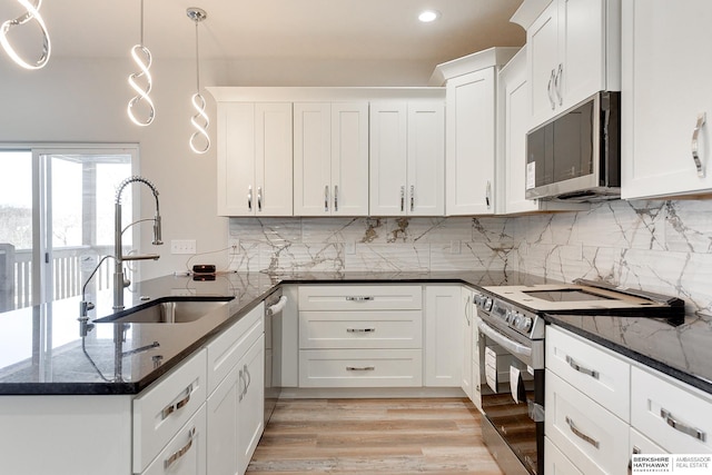 kitchen featuring dark stone countertops, sink, hanging light fixtures, appliances with stainless steel finishes, and white cabinets