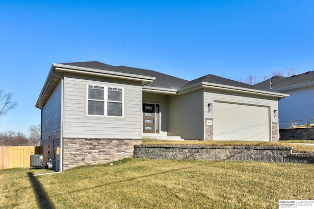 view of front of house with a garage, a front yard, and central AC