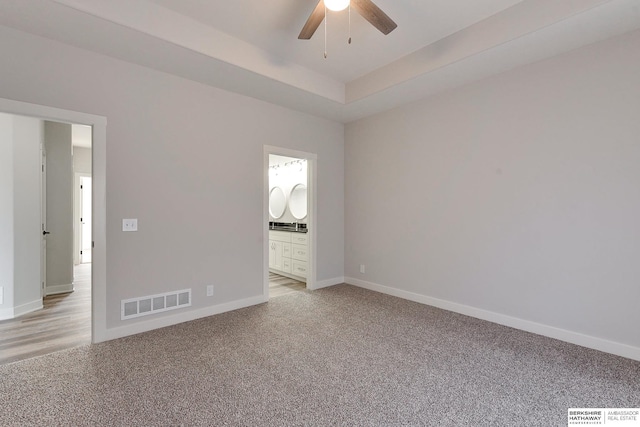 carpeted empty room with ceiling fan and a tray ceiling