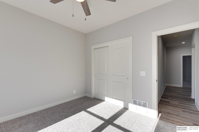 unfurnished bedroom featuring ceiling fan, a closet, and dark colored carpet