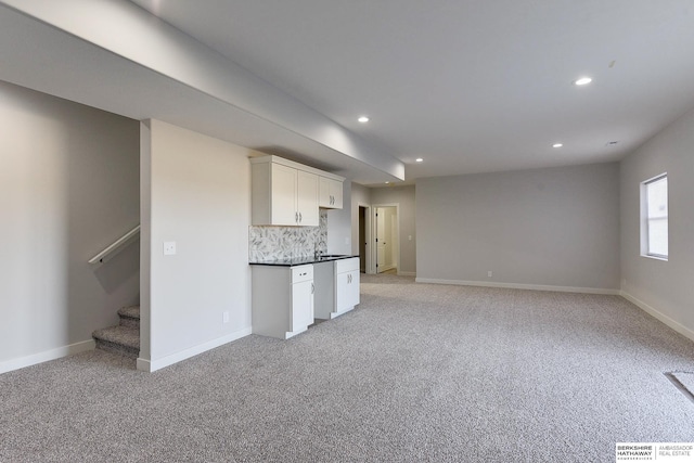 kitchen with light carpet, white cabinetry, and backsplash