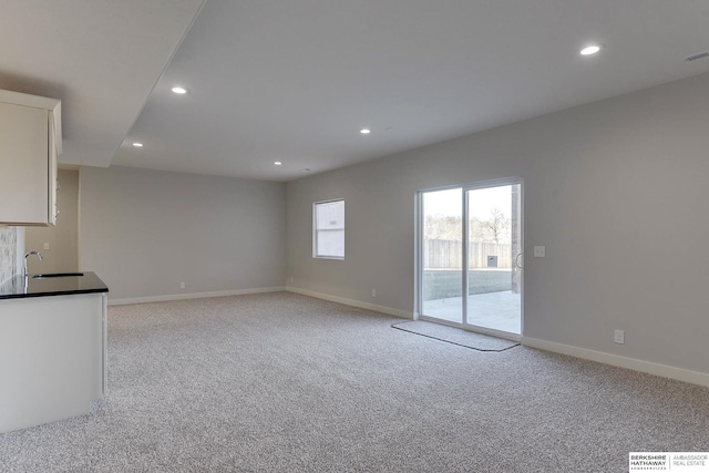 unfurnished living room with light carpet and sink