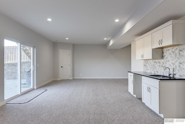 kitchen featuring light carpet, decorative backsplash, sink, and white cabinetry