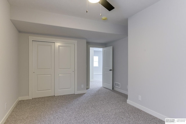 unfurnished bedroom with a closet, light colored carpet, and ceiling fan