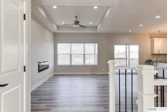 living room with ceiling fan, a raised ceiling, dark hardwood / wood-style floors, and heating unit