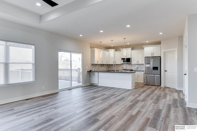 kitchen featuring tasteful backsplash, pendant lighting, light wood-type flooring, stainless steel appliances, and white cabinets