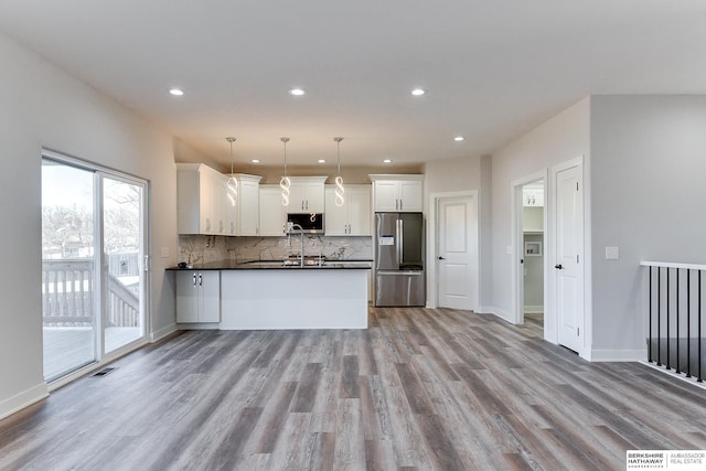 kitchen with pendant lighting, white cabinets, appliances with stainless steel finishes, light hardwood / wood-style floors, and backsplash