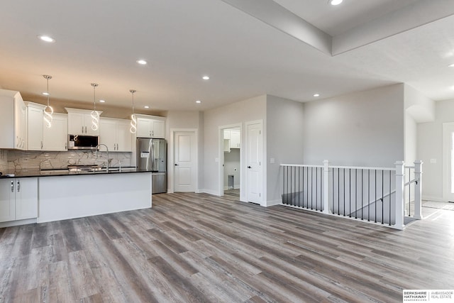 kitchen featuring backsplash, light hardwood / wood-style floors, pendant lighting, appliances with stainless steel finishes, and white cabinets