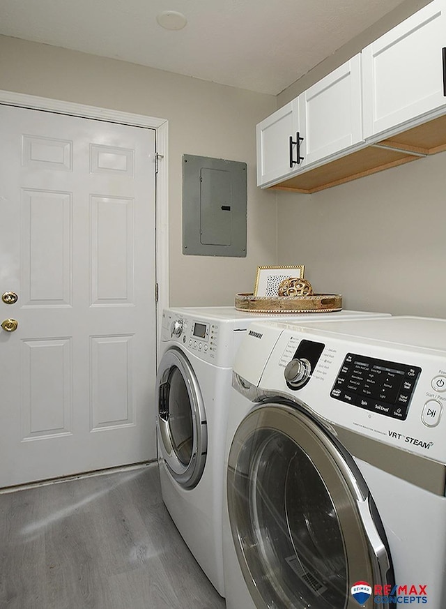 washroom featuring light hardwood / wood-style floors, cabinets, electric panel, and separate washer and dryer