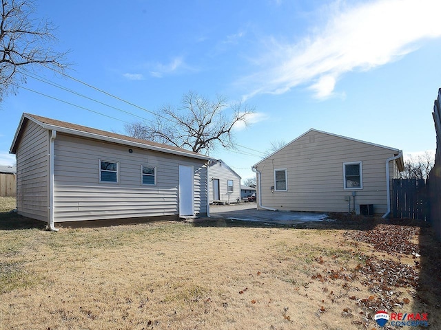 back of house with cooling unit and a lawn