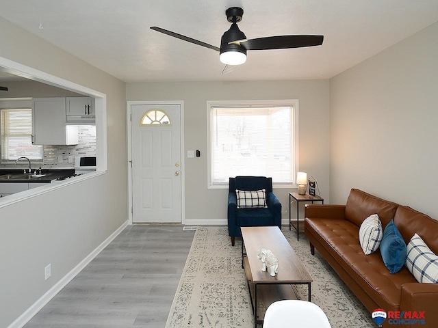 living room featuring ceiling fan, light wood-type flooring, and sink