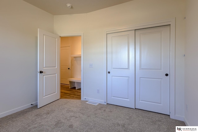 unfurnished bedroom with light colored carpet and a closet