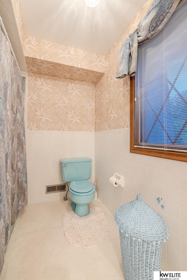 bathroom featuring tile walls and toilet