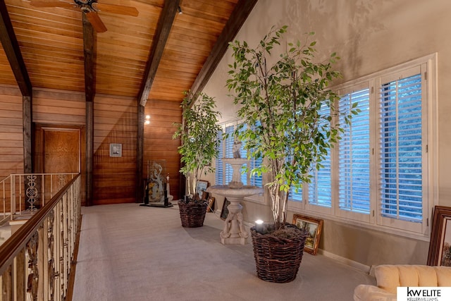 sitting room featuring ceiling fan, wooden ceiling, wood walls, and vaulted ceiling with beams