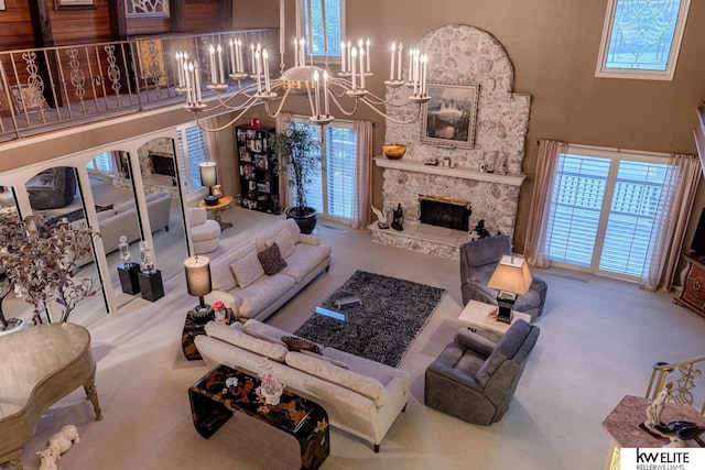 carpeted living room with a towering ceiling, a stone fireplace, and a notable chandelier