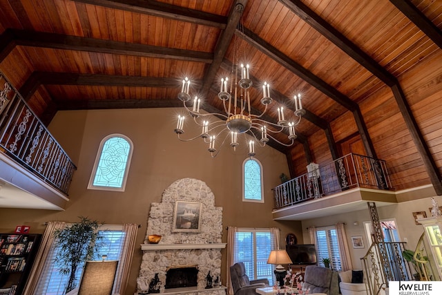 unfurnished living room featuring beamed ceiling, a stone fireplace, high vaulted ceiling, a chandelier, and wooden ceiling