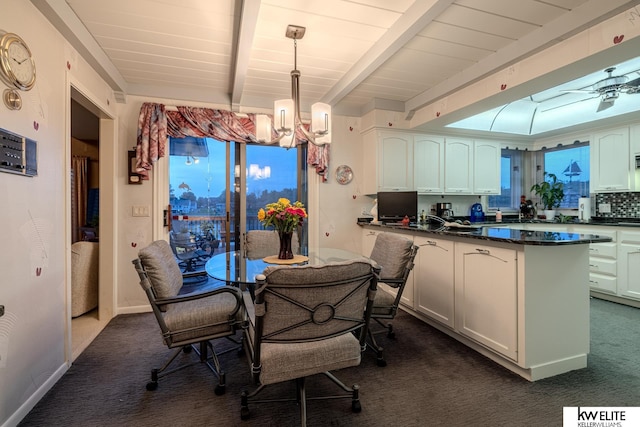 dining area featuring beamed ceiling, ceiling fan with notable chandelier, and dark carpet