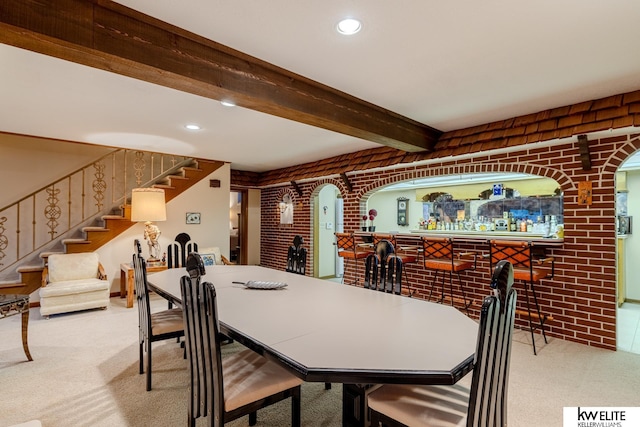 dining area with brick wall, beam ceiling, and carpet floors