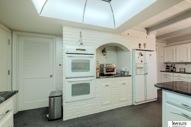 kitchen featuring brick wall, white cabinetry, white appliances, and beam ceiling