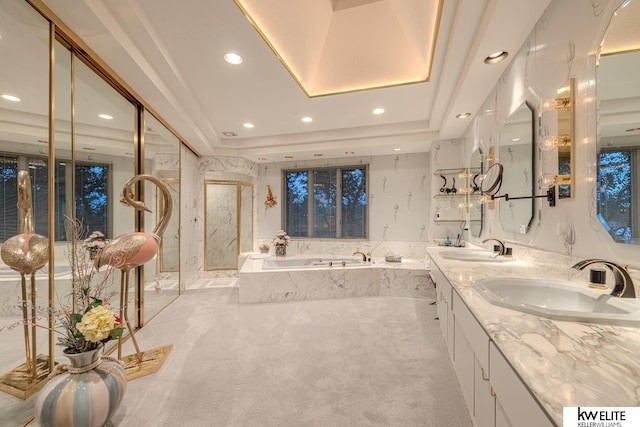 bathroom featuring tiled bath, vanity, and a raised ceiling