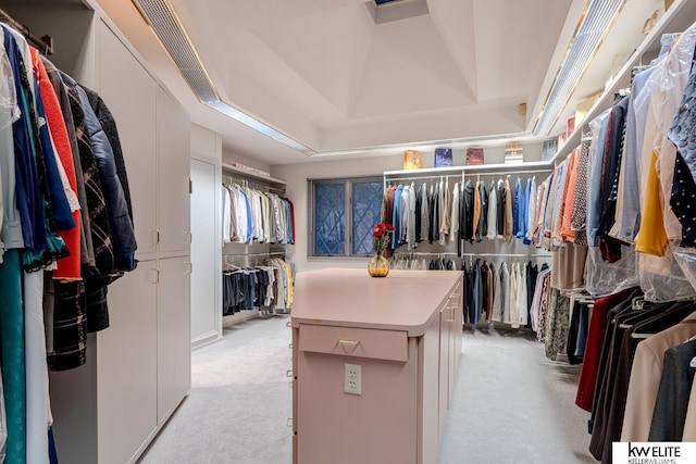 walk in closet with a raised ceiling and light colored carpet