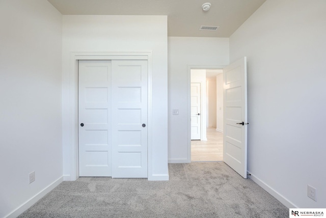 unfurnished bedroom with a closet and light carpet