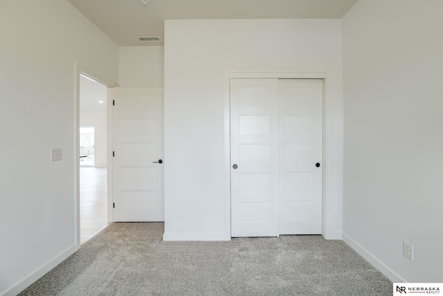 unfurnished bedroom with a closet and light colored carpet