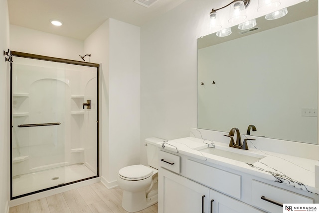 bathroom with toilet, a shower with shower door, hardwood / wood-style floors, and vanity