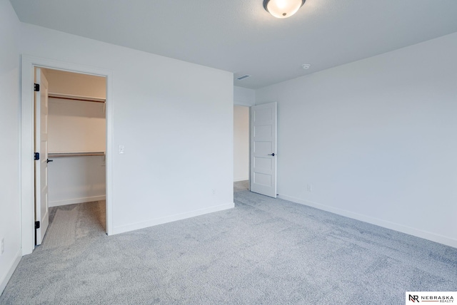 unfurnished bedroom with light colored carpet, a closet, and a spacious closet