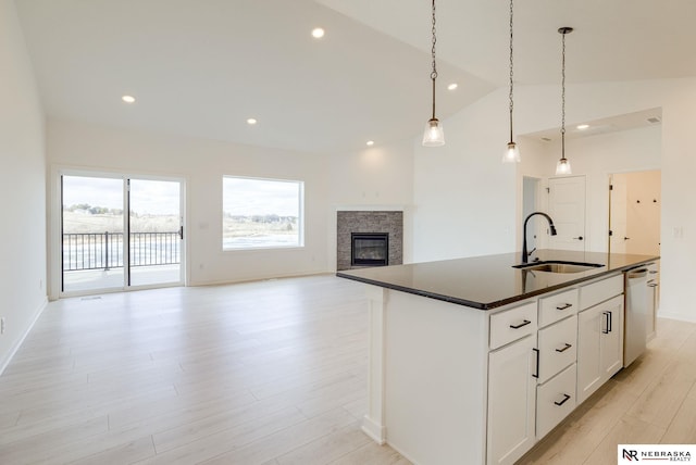 kitchen with a center island with sink, dishwasher, vaulted ceiling, white cabinets, and sink