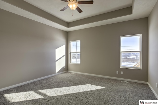 carpeted empty room with a tray ceiling and ceiling fan