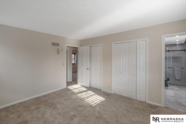 unfurnished bedroom featuring connected bathroom, two closets, and light colored carpet