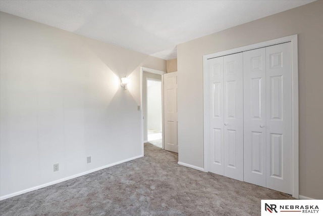 unfurnished bedroom with light colored carpet and a closet