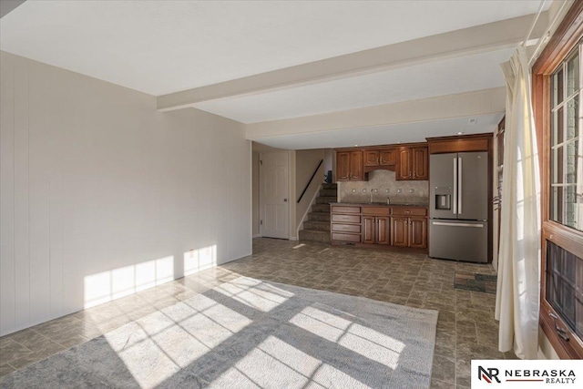 kitchen featuring stainless steel fridge with ice dispenser, a healthy amount of sunlight, tasteful backsplash, and sink