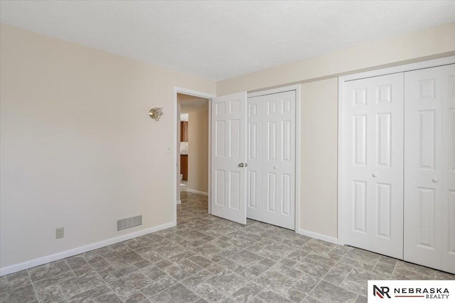 unfurnished bedroom featuring a textured ceiling and two closets